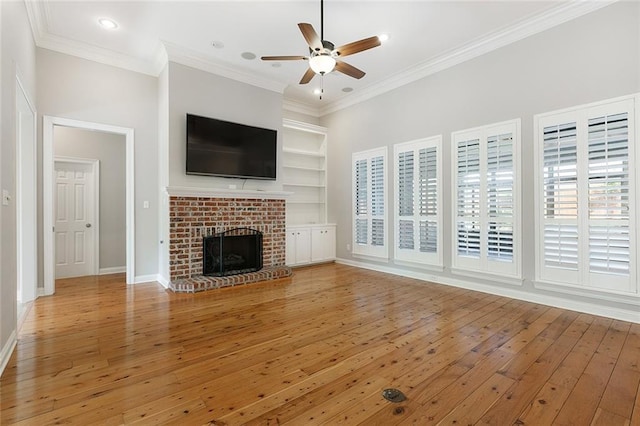 unfurnished living room with hardwood / wood-style floors, ceiling fan, ornamental molding, and a brick fireplace