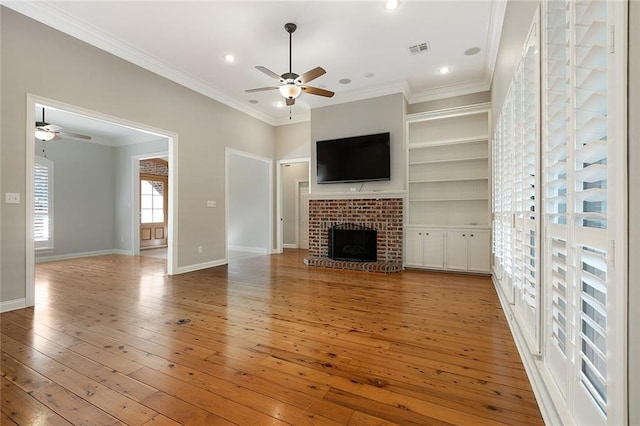 unfurnished living room featuring a brick fireplace, ceiling fan, light hardwood / wood-style floors, and ornamental molding