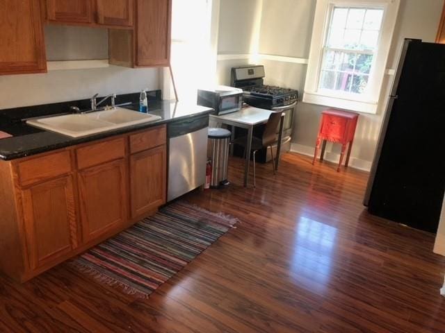928 Independence St, New Orleans, LA 70117 - kitchen with dark countertops, baseboards, dark wood-type flooring, a sink, and appliances with stainless steel finishes