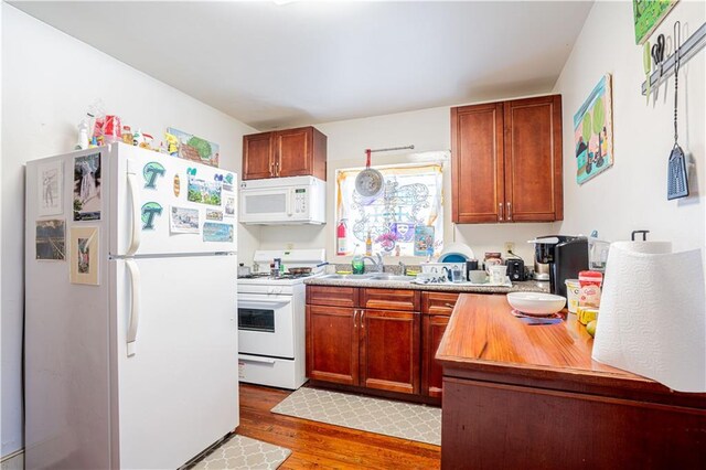 kitchen with light hardwood / wood-style floors, white appliances, and sink