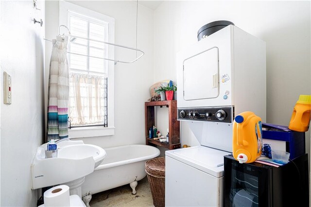 bathroom with a bathing tub, toilet, and stacked washing maching and dryer