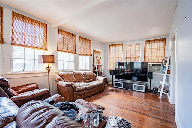 living room featuring cooling unit, beamed ceiling, and hardwood / wood-style flooring