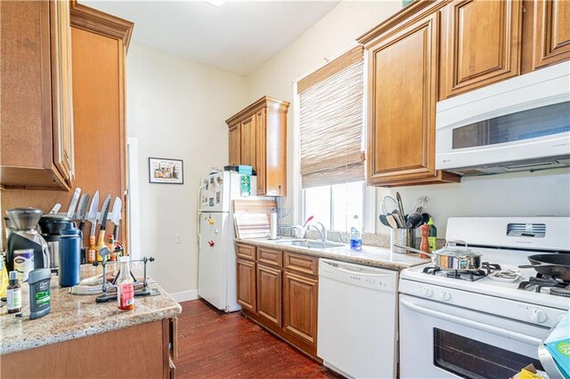 kitchen featuring light stone countertops, sink, dark hardwood / wood-style floors, and white appliances