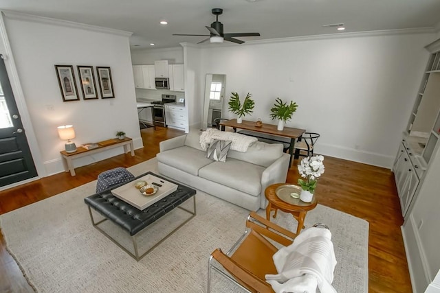 living room with ornamental molding, hardwood / wood-style flooring, and ceiling fan