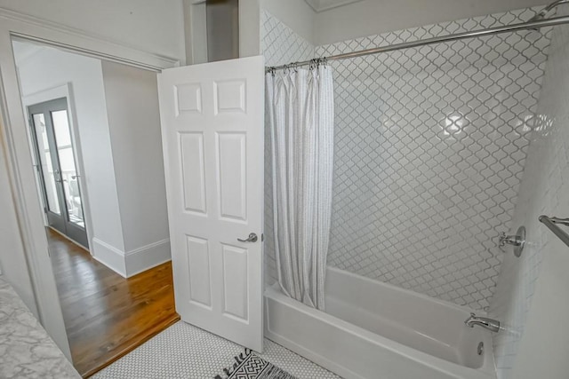 bathroom featuring french doors, hardwood / wood-style flooring, and shower / bathtub combination with curtain