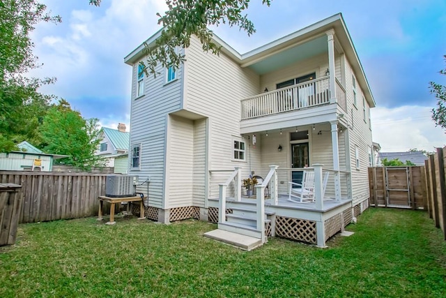 rear view of property featuring a lawn, central AC, and a balcony