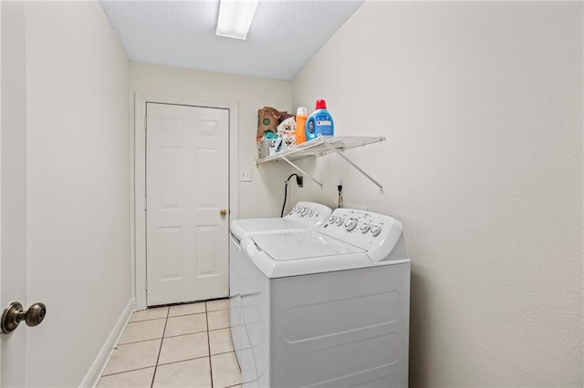 laundry room featuring a textured ceiling, washer and clothes dryer, and light tile patterned flooring