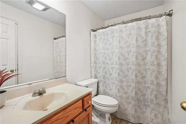 bathroom with toilet, vanity, a textured ceiling, and tile patterned floors