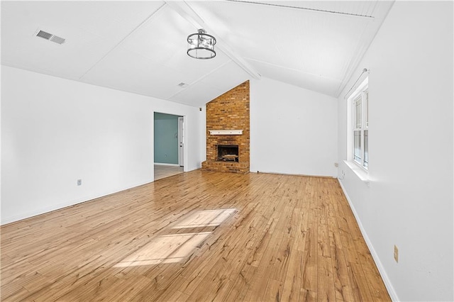 unfurnished living room featuring a fireplace, light hardwood / wood-style flooring, and lofted ceiling with beams