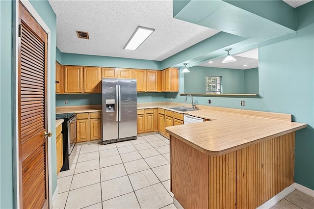 kitchen with sink, kitchen peninsula, stainless steel refrigerator with ice dispenser, a textured ceiling, and range