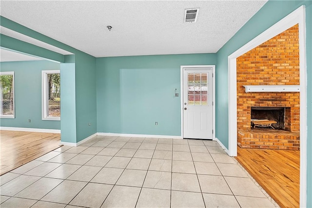 unfurnished living room featuring plenty of natural light, a textured ceiling, and light hardwood / wood-style flooring