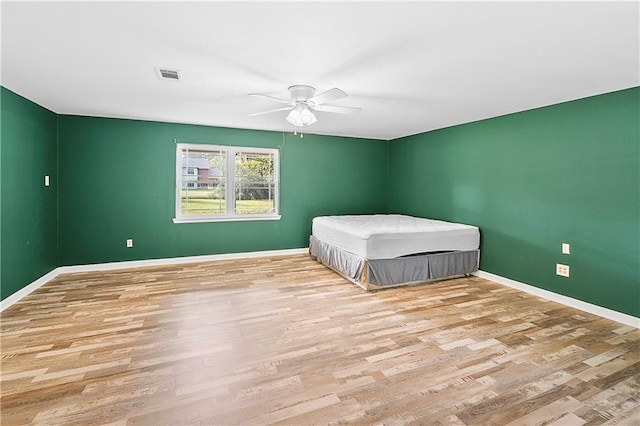 unfurnished bedroom featuring wood finished floors, baseboards, and ceiling fan
