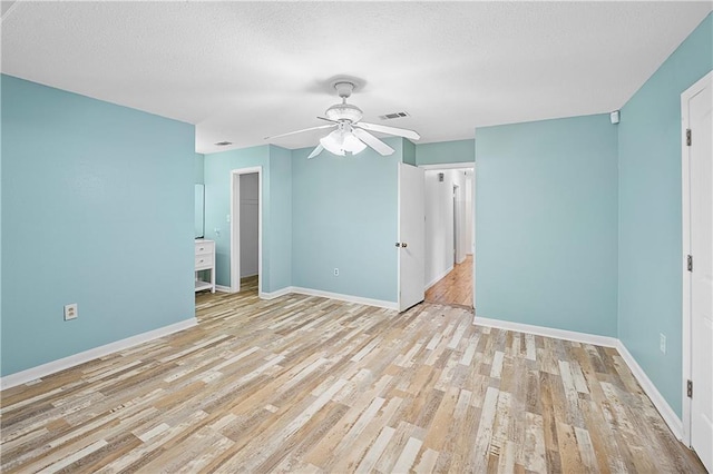 unfurnished room featuring light wood-style flooring, baseboards, ceiling fan, and a textured ceiling