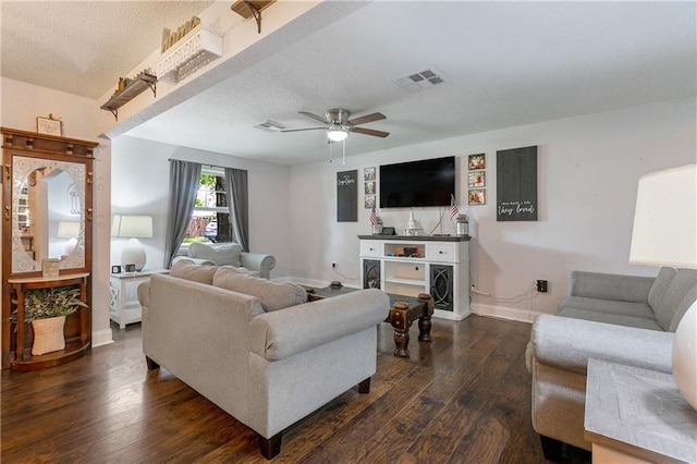 living room with dark wood-type flooring, ceiling fan, and a textured ceiling