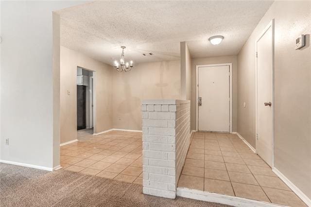 hall with light carpet, a textured ceiling, and an inviting chandelier