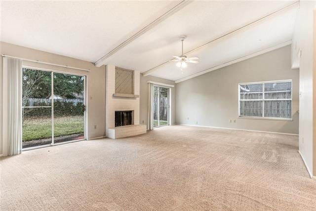 unfurnished living room featuring carpet flooring, vaulted ceiling with beams, a large fireplace, and ceiling fan