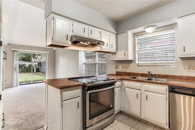 kitchen featuring light carpet, a textured ceiling, stainless steel appliances, sink, and white cabinets