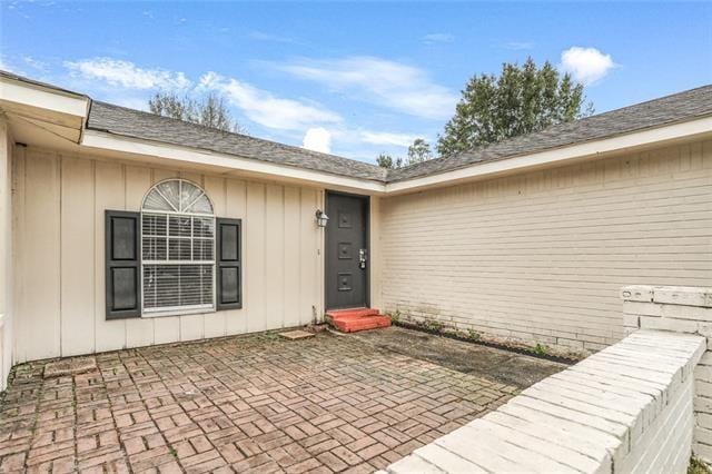 view of exterior entry with a patio area