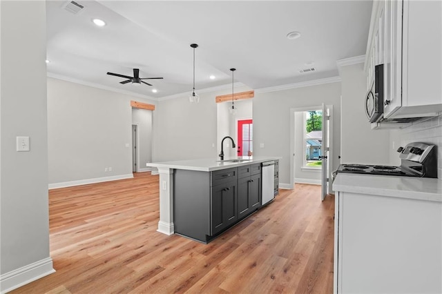 kitchen featuring hanging light fixtures, light hardwood / wood-style flooring, stainless steel appliances, and a center island with sink