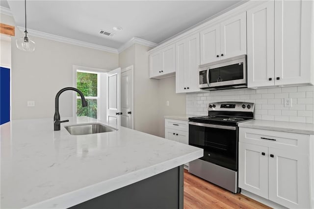 kitchen featuring pendant lighting, sink, crown molding, appliances with stainless steel finishes, and white cabinets