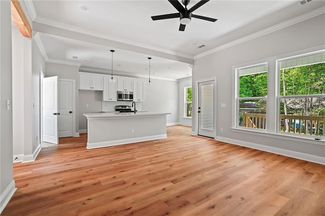 kitchen featuring hanging light fixtures, ornamental molding, a kitchen island with sink, light hardwood / wood-style floors, and white cabinets