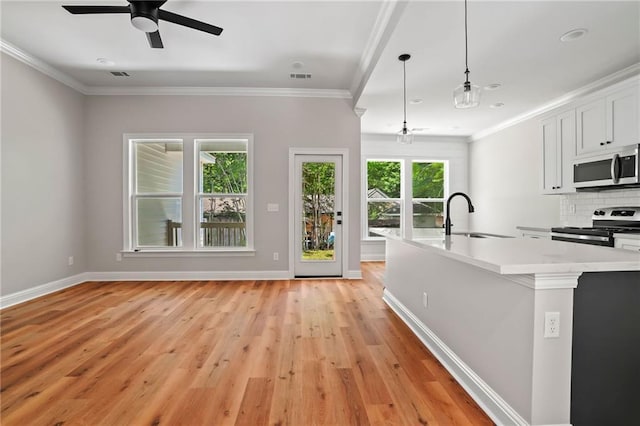 kitchen featuring pendant lighting, sink, crown molding, stainless steel appliances, and white cabinets