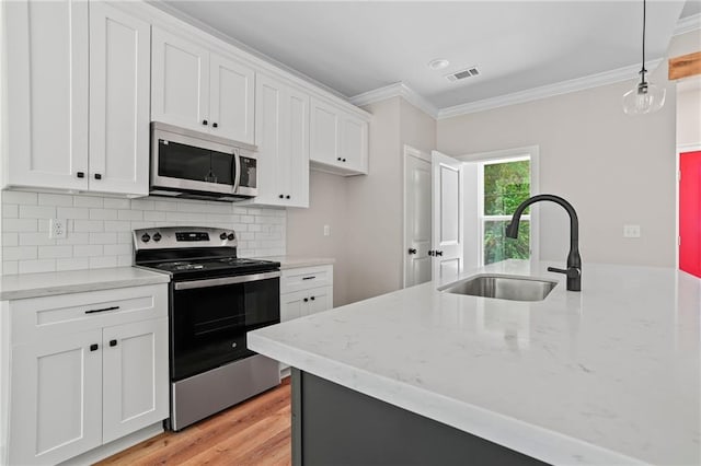 kitchen with appliances with stainless steel finishes, white cabinets, and decorative light fixtures