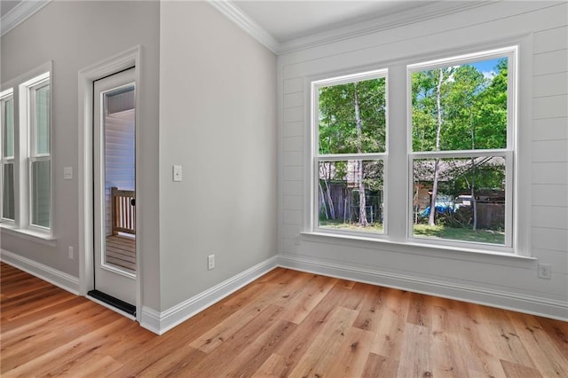 empty room with crown molding and light wood-type flooring