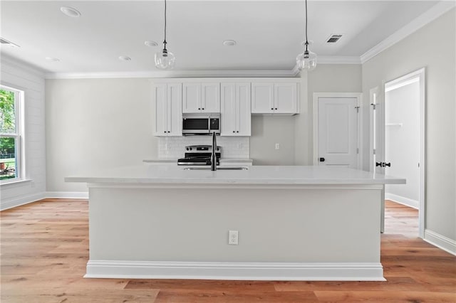 kitchen with stainless steel appliances, decorative light fixtures, a center island with sink, and white cabinets