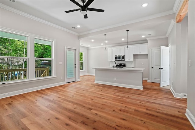 kitchen featuring ornamental molding, a center island with sink, white cabinets, and decorative light fixtures