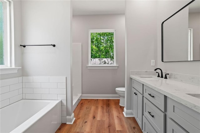 bathroom featuring vanity, a bath, hardwood / wood-style floors, and toilet