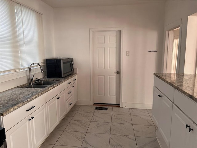 3633 Franklin Ave, New Orleans, LA 70122 - kitchen featuring stainless steel microwave, a sink, light marble finish floors, white cabinetry, and stone countertops