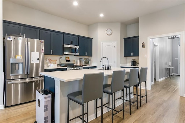 kitchen featuring sink, an island with sink, light hardwood / wood-style floors, and stainless steel appliances