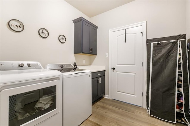 clothes washing area featuring light wood-type flooring, cabinets, and independent washer and dryer