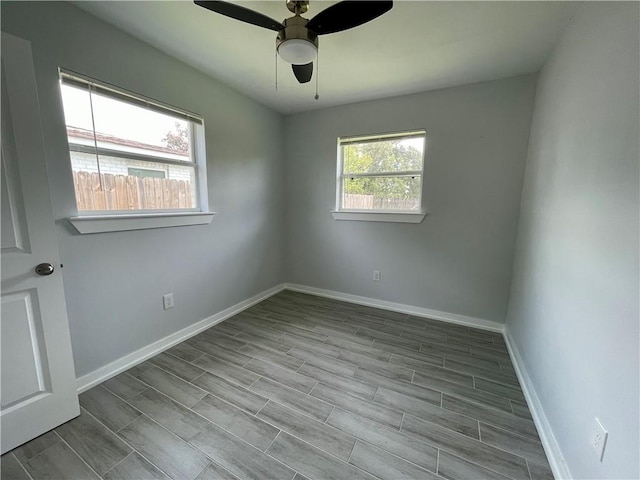 empty room featuring a wealth of natural light, ceiling fan, and light wood-type flooring