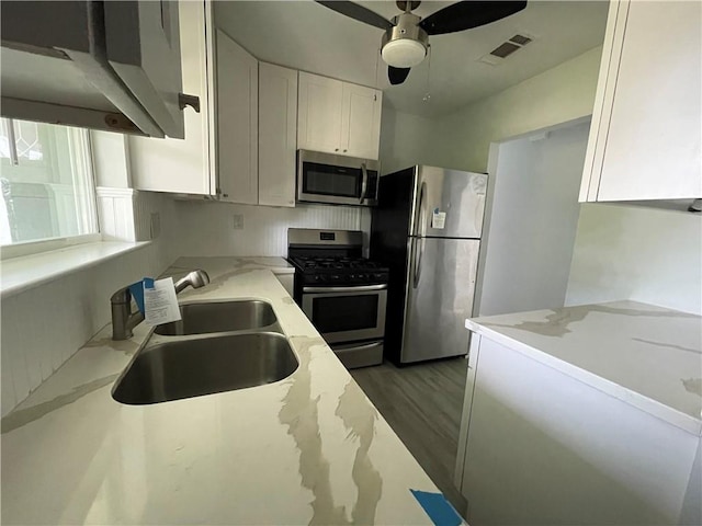 kitchen with stainless steel appliances, light stone counters, white cabinets, sink, and dark hardwood / wood-style floors