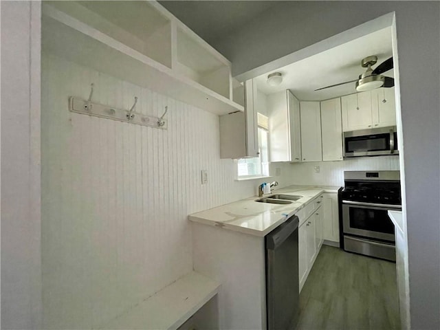 kitchen with white cabinets, hardwood / wood-style flooring, sink, ceiling fan, and appliances with stainless steel finishes