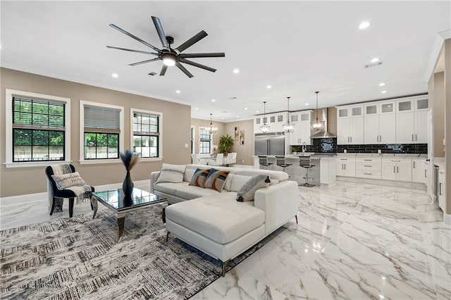 living area with ornamental molding, ceiling fan with notable chandelier, marble finish floor, and recessed lighting