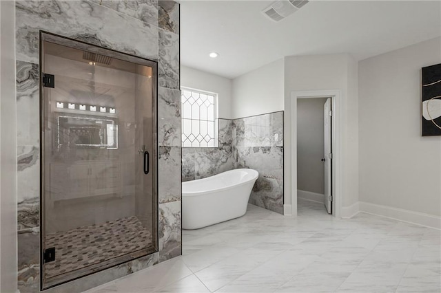 full bathroom with marble finish floor, visible vents, a stall shower, a freestanding bath, and baseboards