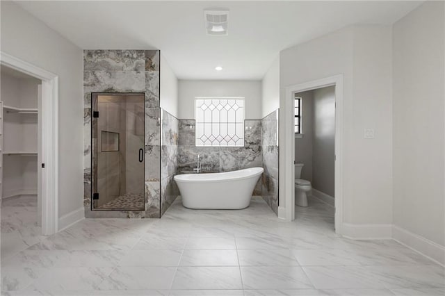 bathroom with a stall shower, tile walls, toilet, marble finish floor, and a freestanding tub