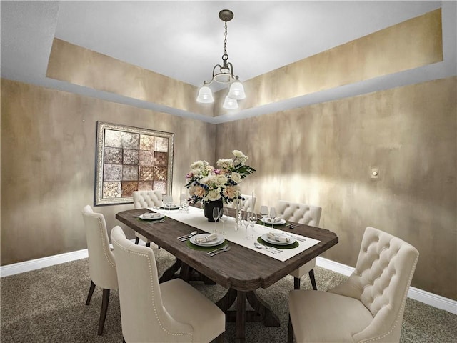 dining area featuring a notable chandelier, dark carpet, and a raised ceiling