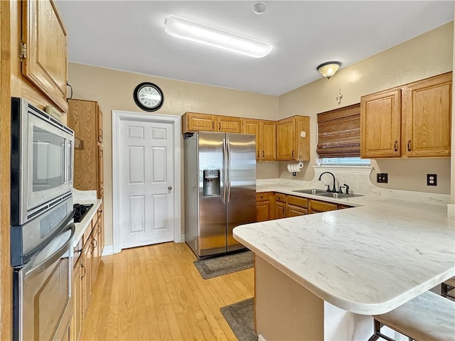 kitchen featuring kitchen peninsula, sink, a kitchen bar, and stainless steel appliances