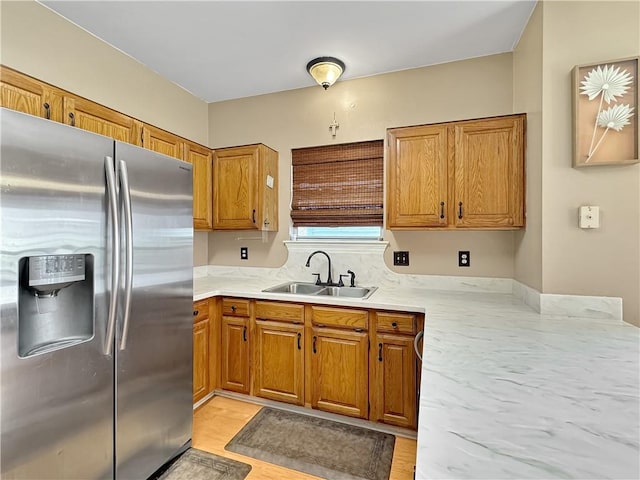 kitchen with stainless steel refrigerator with ice dispenser, light hardwood / wood-style floors, and sink