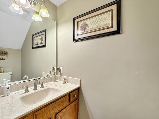 bathroom featuring vanity, toilet, and vaulted ceiling