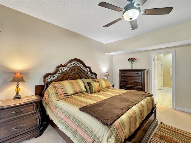 bedroom featuring ensuite bathroom, ceiling fan, a textured ceiling, and light carpet