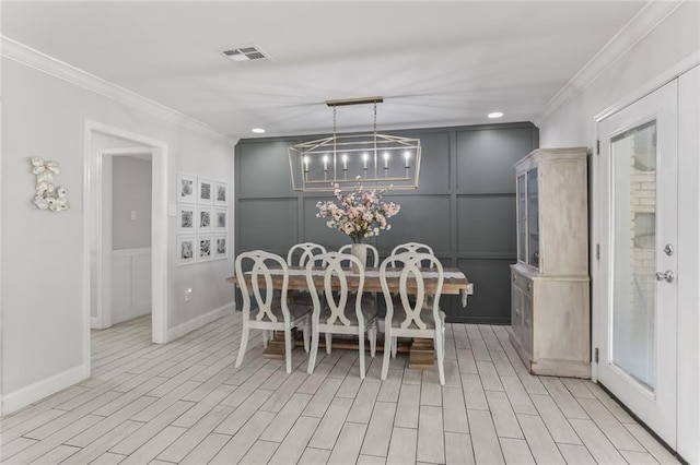 dining area with ornamental molding, light wood-type flooring, and a notable chandelier