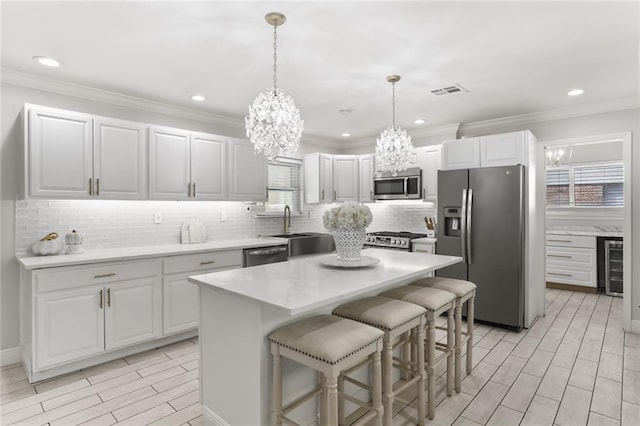 kitchen featuring wine cooler, appliances with stainless steel finishes, hanging light fixtures, white cabinets, and a center island