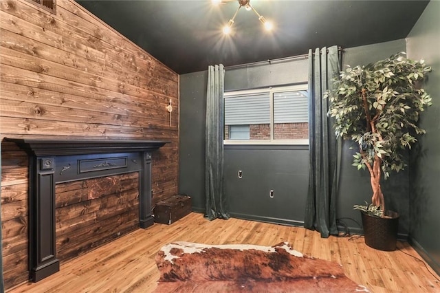 bedroom featuring wooden walls, light hardwood / wood-style flooring, and vaulted ceiling