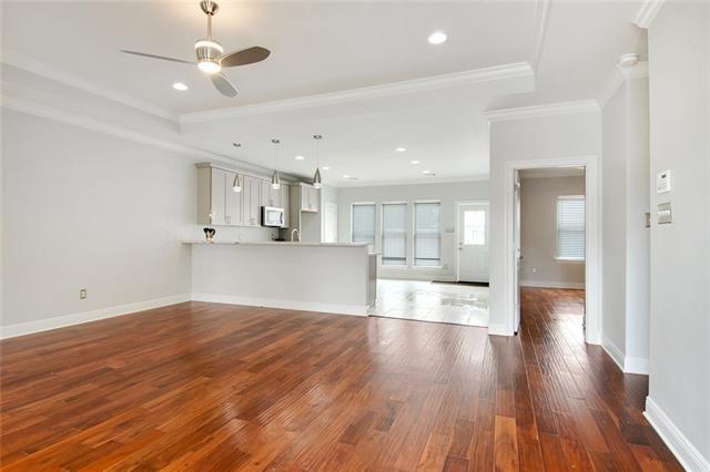 unfurnished living room with ceiling fan, dark hardwood / wood-style flooring, and crown molding