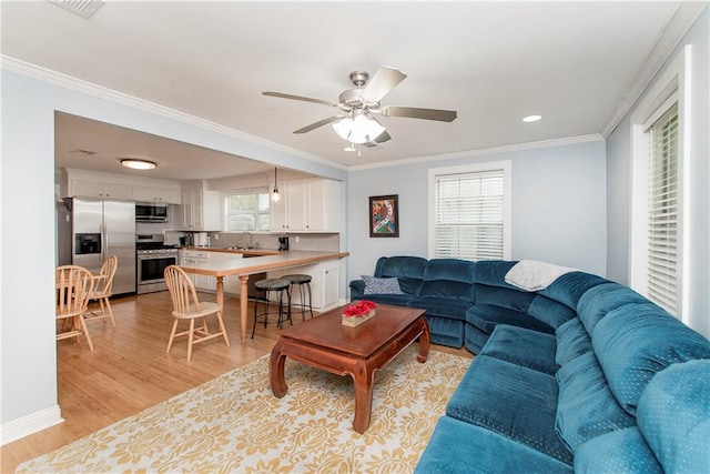 living room with ceiling fan, sink, light wood-type flooring, and ornamental molding